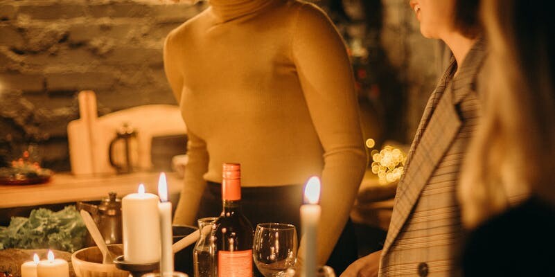 Warm and inviting dinner party scene with candles illuminating smiling guests.