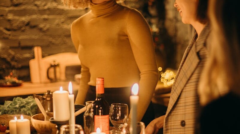 Warm and inviting dinner party scene with candles illuminating smiling guests.
