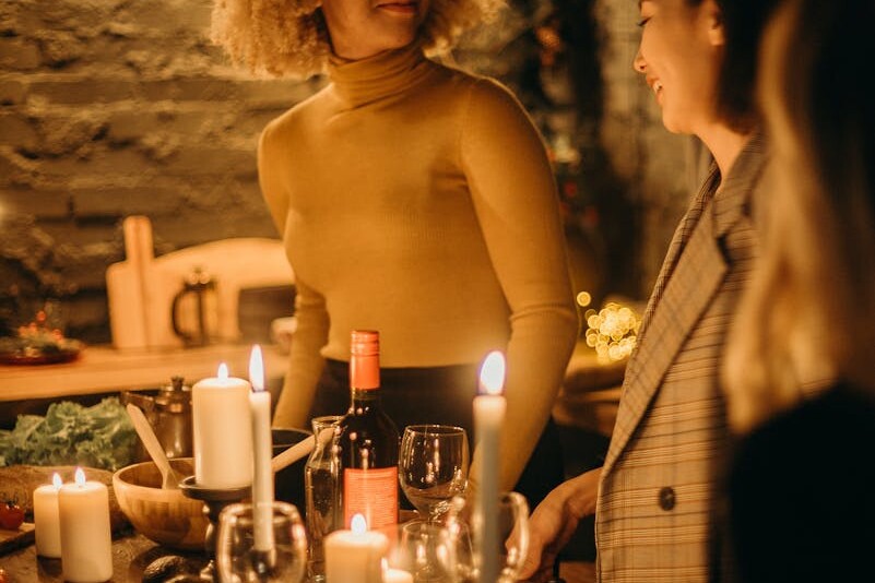 Warm and inviting dinner party scene with candles illuminating smiling guests.