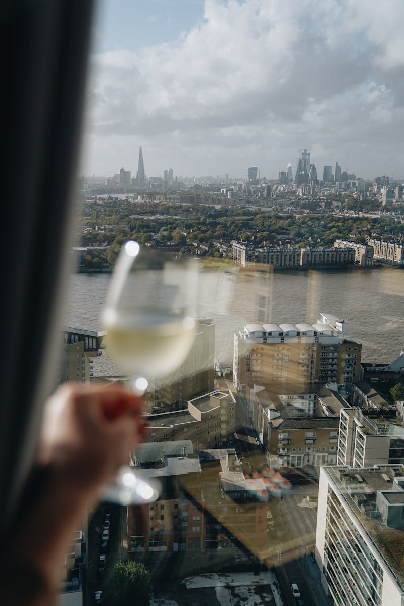 A breathtaking view of London's skyline with a glass of white wine, captured from a high vantage point.
